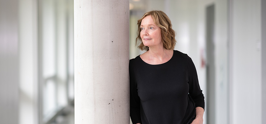 Dr. Lori Harper leans against a pillar in Allard Hall wearing a black shirt